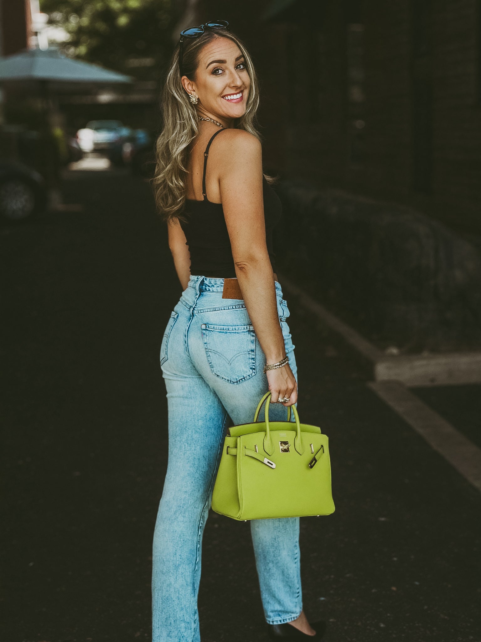 Woman holding a lime green handbag on a street